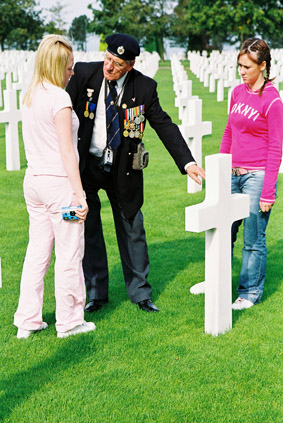 image of two girls at a war grave  talkng with a veteran