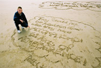 image of boy on a normandy beach with his poem in the sand